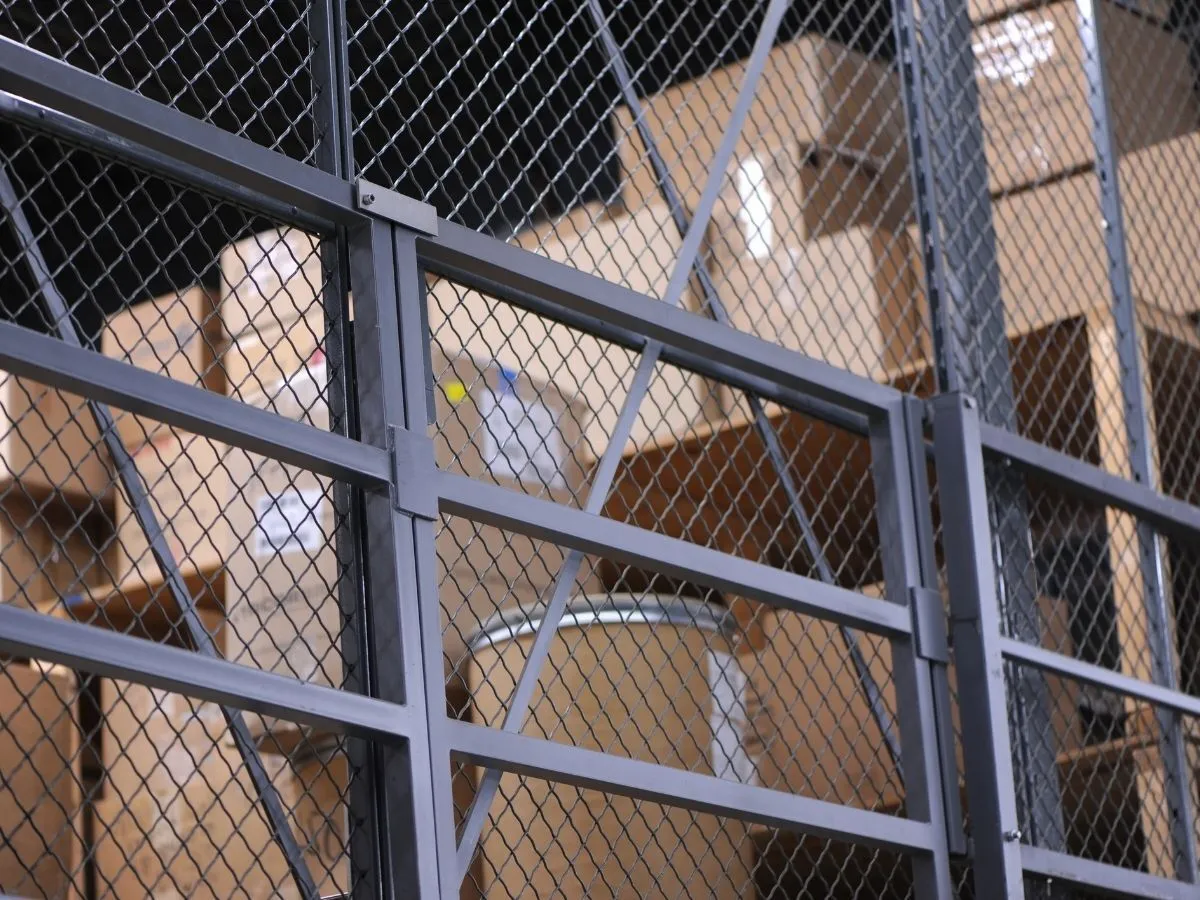 A galvanised mesh security storage cage in a warehouse dispatch area.