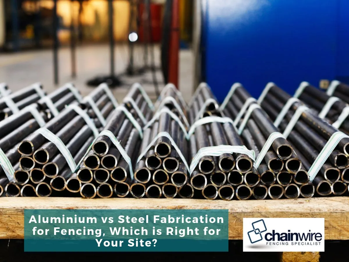 Bundles of steel tubing on a pallet in a fabrication workshop, titled Aluminium vs Steel Fabrication for Fencing