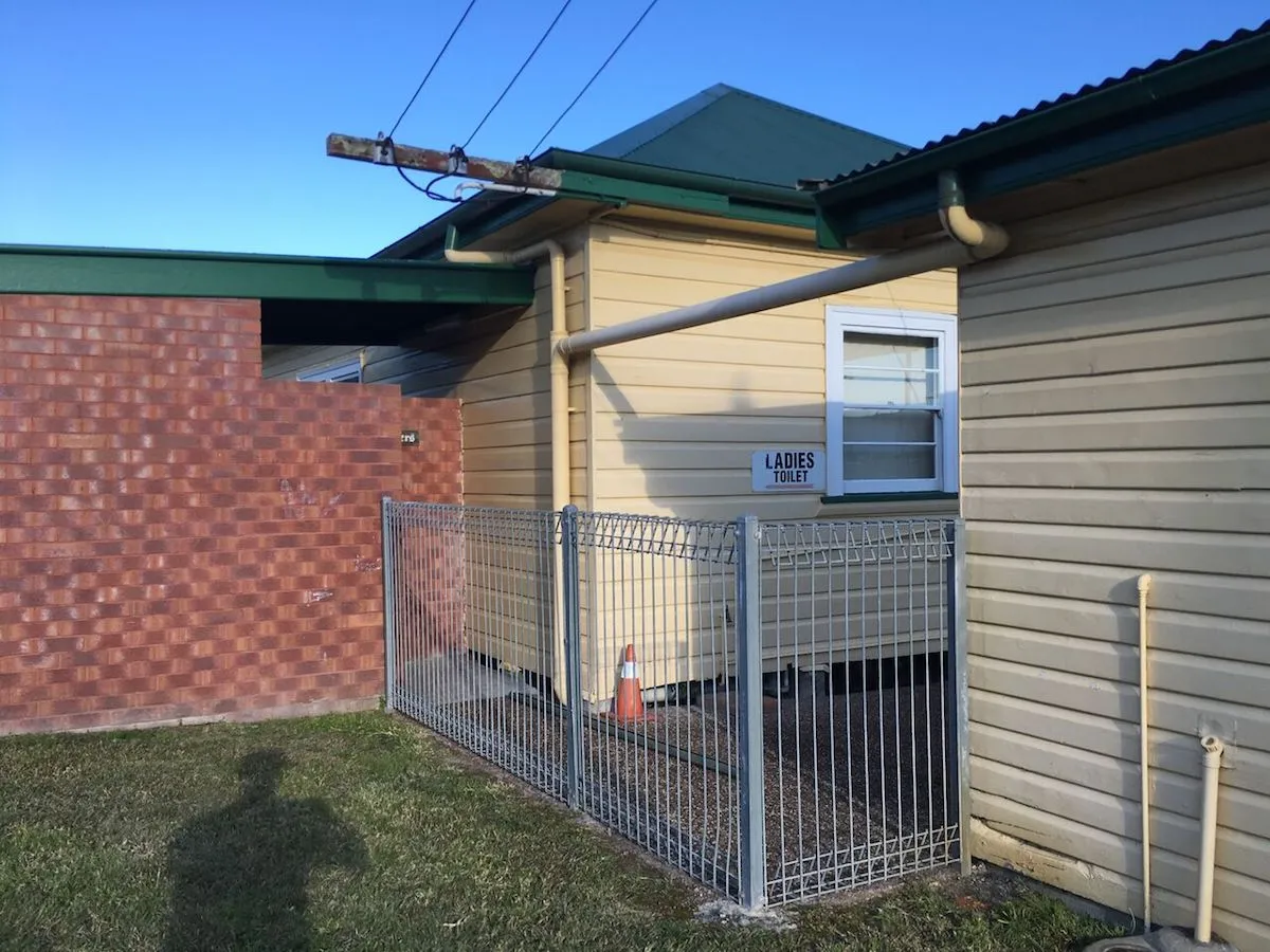 Galvanised welded-mesh fencing around a public amenities block