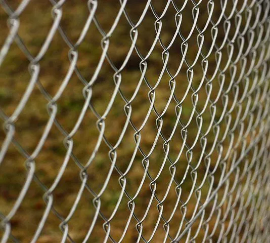 A galvanised chainwire fence with top and bottom rails running along an open boundary.