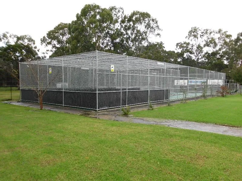 A multi-lane cricket practice net under construction with galvanised steel framing.