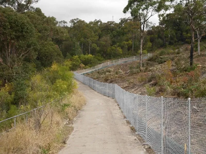Galvanised mesh fencing running alongside a sealed shared path.