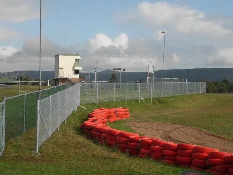 Galvanised chainwire fencing running alongside a go-kart track.