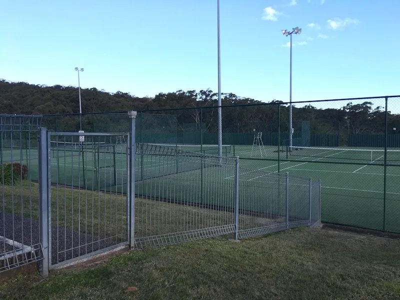 Galvanised chainwire fencing enclosing tennis courts
