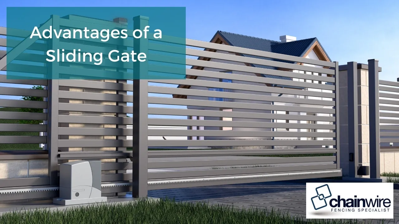 Automated sliding gate on a track alongside a chainwire fence at a property entrance