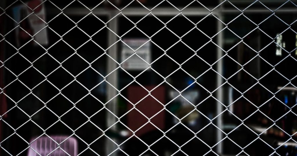 Close-up of a silver chain-link fence with a dark, blurred background.