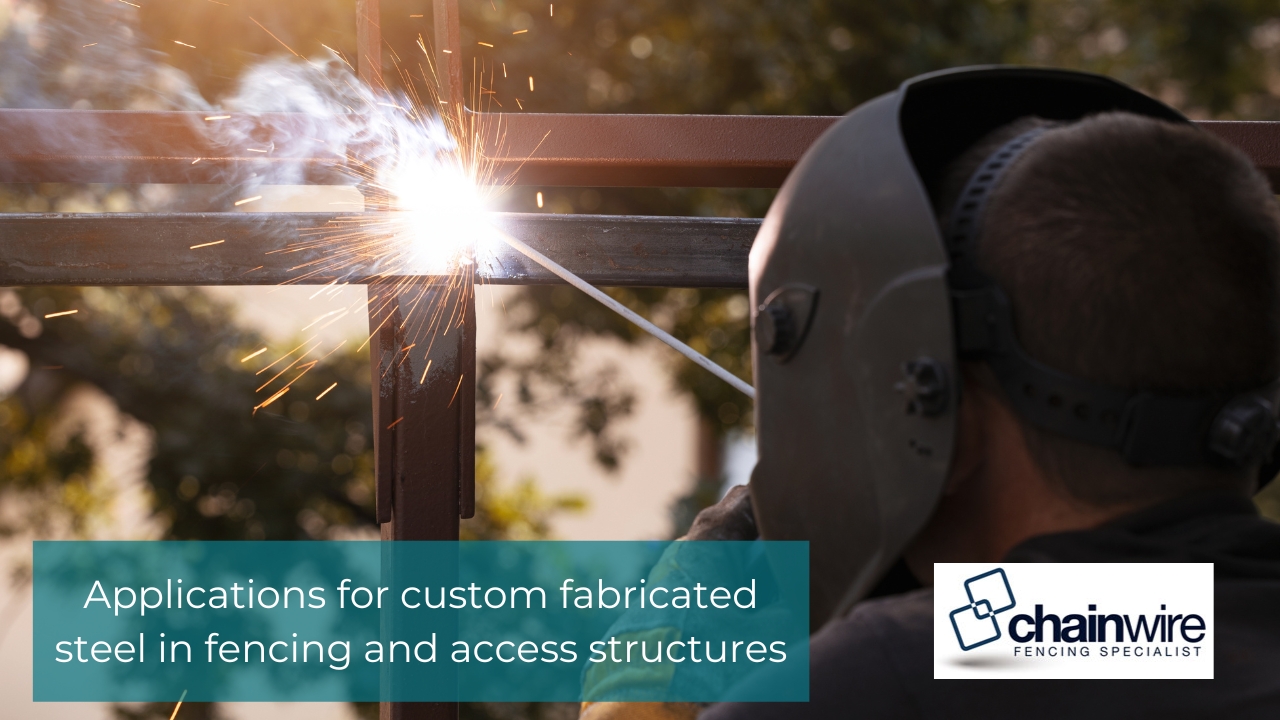 A welder in protective gear uses an arc welder on a steel fence frame, creating bright sparks and smoke.
